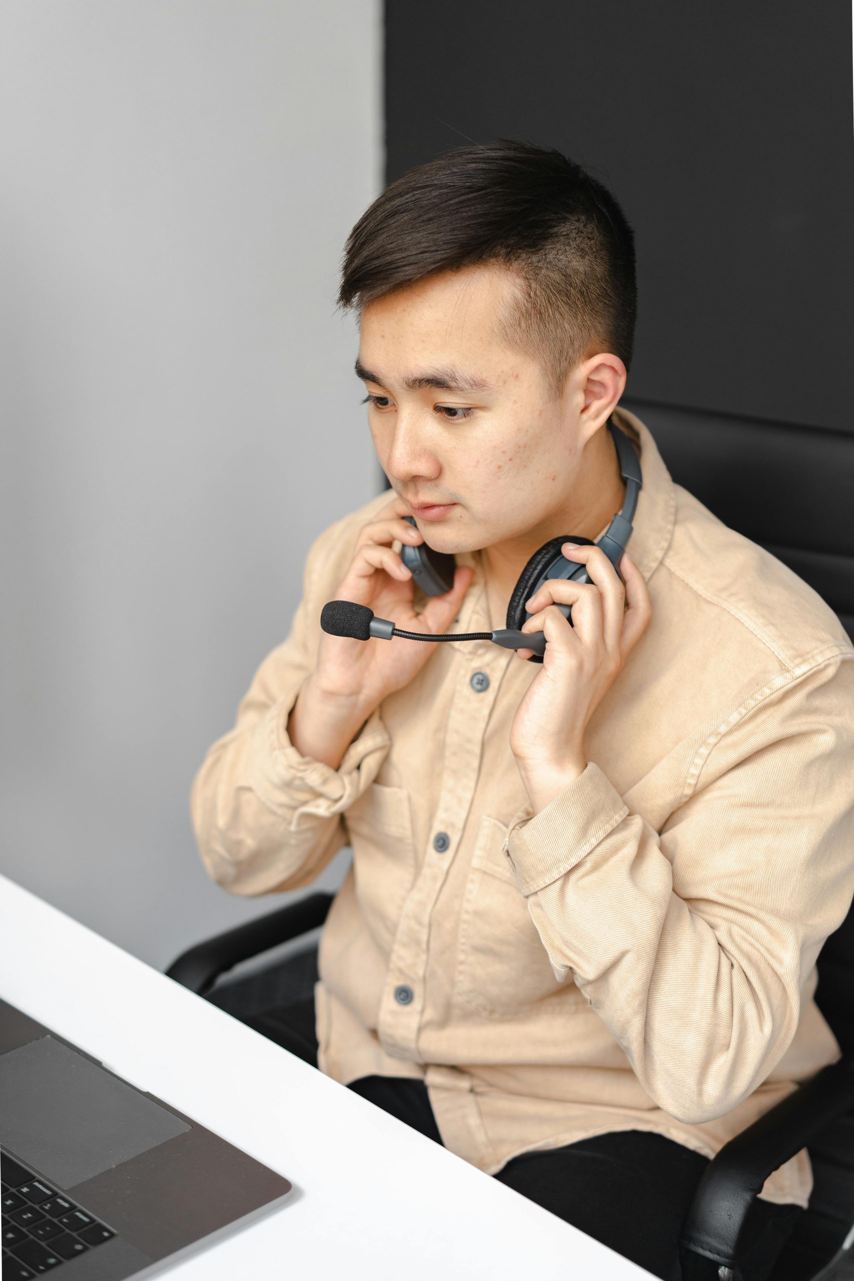 Asian male technical support agent wearing a headset and working on a laptop.